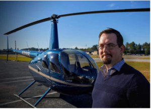 Man in his late 40's stands in front of helicopter.