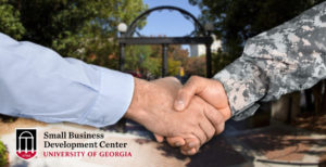 Civilian and soldier shake hands in front of the arch, SBDC logo in corner