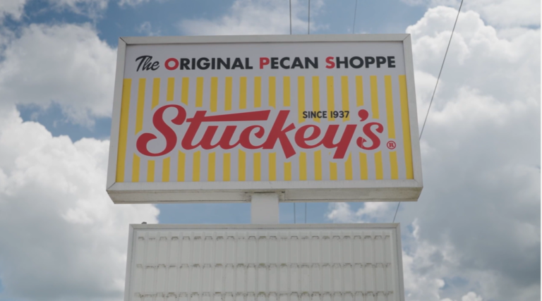 Large roadside sign reading “The Original Pecan Shoppe — Stuckey’s — Since 1937” against a partly cloudy sky.