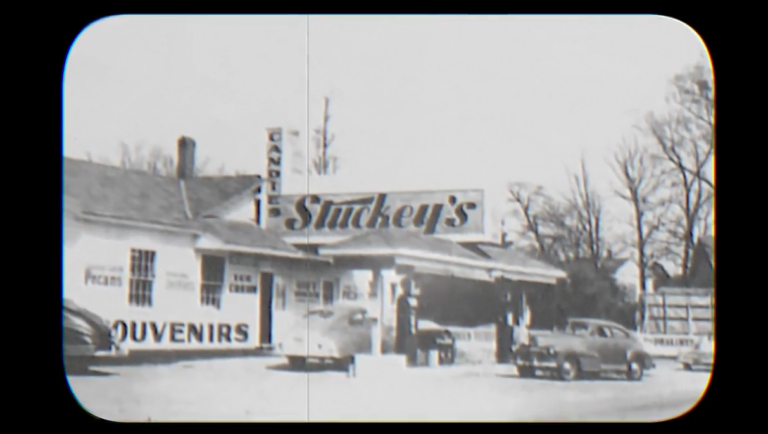 Vintage black‑and‑white photograph of an early Stuckey’s roadside store with large signage reading “Stuckey’s,” “Pecans,” and “Souvenirs,” surrounded by parked cars.