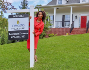 Labresia Dawson poses with real estate sign in front of home