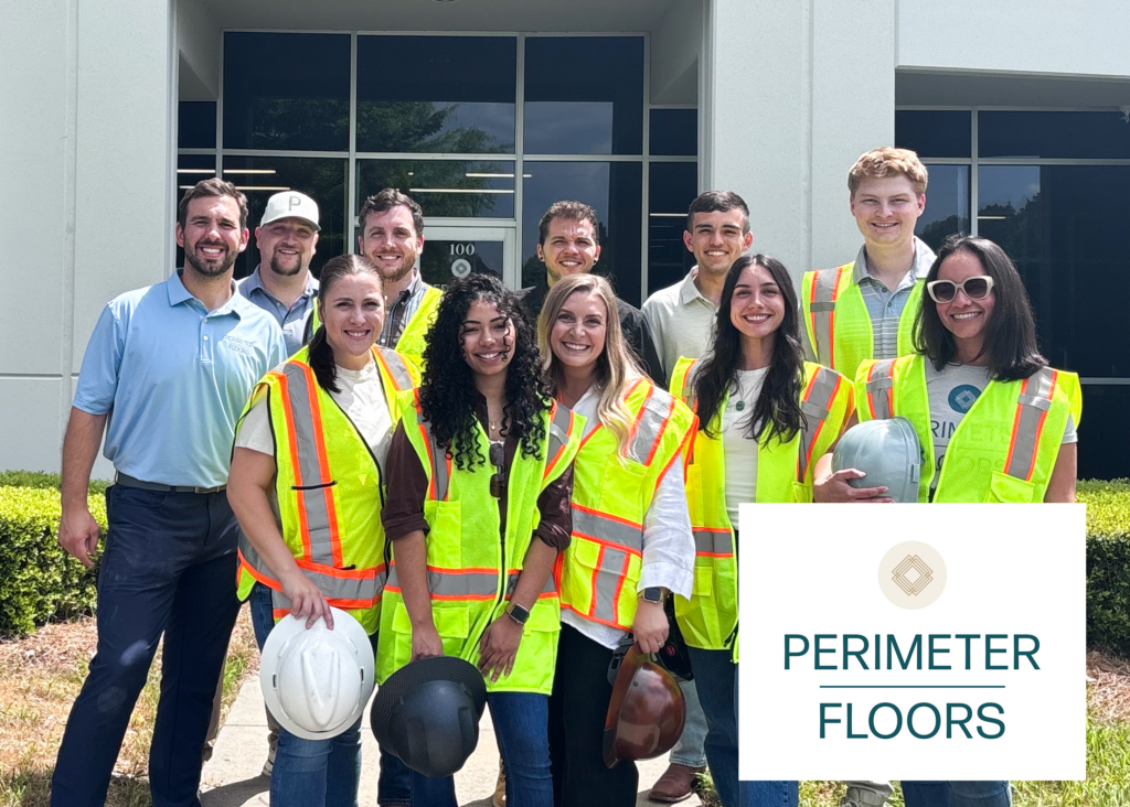 Perimeter Floors team members stand outside company headquarters in Cobb County wearing safety vests and hard hats after the company's growth supported by UGA SBDC consulting. Perimeter Floors logo in lower right.